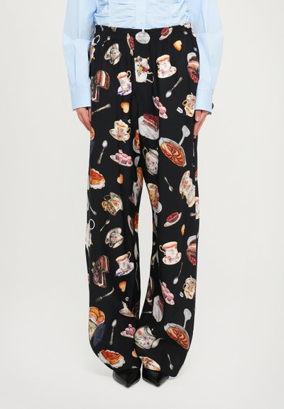 Pantalons larges noirs avec un motif répétitif de desserts, tasses à thé et ustensiles, fabriqués à partir d'un tissu léger avec une taille élastique.