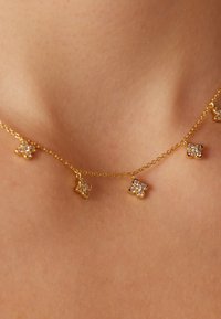Gouden ketting met vijf vlinder-vormige bedels, elk versierd met heldere kristallen, met een delicate ketting en een gladde textuur.