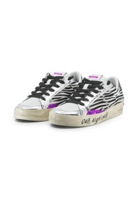Sneakers argentati metallici con stampa zebra, lacci neri, dettagli in glitter viola e suola beige con testo scritto a mano sul lato.