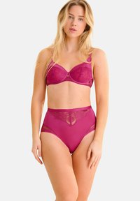 Ensemble de lingerie fuchsia comprenant un soutien-gorge en dentelle avec armatures et une culotte taille haute. Les deux pièces présentent des accents transparents et des motifs floraux.