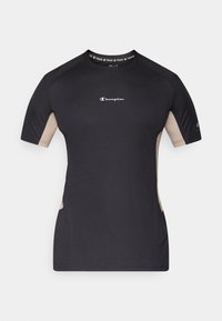 Μαύρο αθλητικό μπλουζάκι με κοντά μανίκια, με μπεζ πλευρικές πάνελ και ριμπ λαιμόκοψη με την επιγραφή «TRAIN». Λογότυπο Champion στο μπροστινό μέρος.