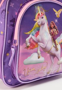 Μωβ υφασμάτινο σακίδιο πλάτης με γραφικό ενός μονόκερου, ουράνιο τόξο στην χαίτη και εικονογράφηση χαρακτήρα. Φ ερμουάρ σε ροζ με το κείμενο «Unicorn Academy».