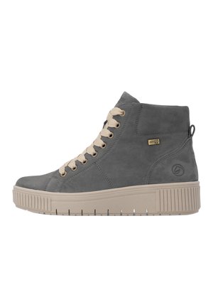 Baskets montantes grises avec semelle et lacets beiges, patch logo sur le côté, semelle texturée et boucle au talon, présentées de profil sur fond blanc.
