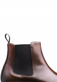 Botte Chelsea en cuir marron avec un panneau latéral élastique noir, finition lisse et une languette au talon pour un enfilage facile.