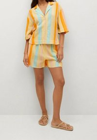 Kurzärmeliges, knöpfbares Hemd und passende Shorts mit vertikalen Streifen in Gelb, Orange, Blau und Pink. Leichter Stoff und lockere Passform.