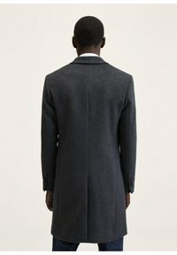 Dunkelgrauer Wollmantel mit taillierter Passform, Reverskragen, langen Ärmeln und sichtbaren Knopfakzenten an den Manschetten. Glatte, strukturierte Textur.