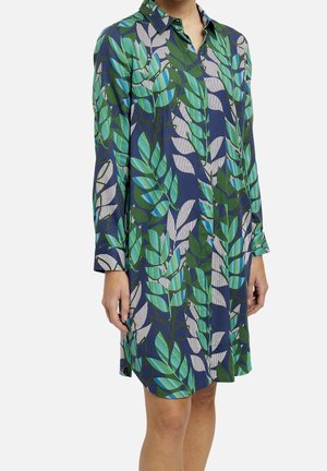 Vestido de manga corta con cuello tipo solapa. Presenta una base azul navy y un patrón de hojas en verde y azul, confeccionado en una tela ligera.