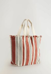 Sac fourre-tout rayé en rouille et crème, avec des lignes verticales et un haut effiloché. Fabriqué en tissu avec deux poignées robustes pour le transport.