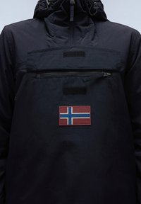 Giacca leggera blu navy con colletto alto, taschino con zip sul petto e una toppa ricamata della bandiera norvegese rossa e blu sul davanti.
