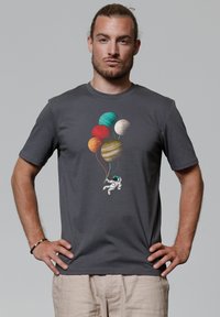 Grijze katoenen T-shirt met een astronaut die kleurrijke planetenballonnen vasthoudt. Het ontwerp is gecentreerd op de voorkant. Korte mouwen, ronde halsstijl.