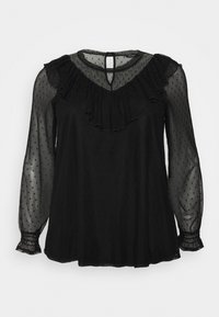 Blusa nera con maniche trasparenti a pois e scollo con volant. Presenta chiusura con bottoni sul retro e polsini elasticizzati. Tessuto morbido e fluido.