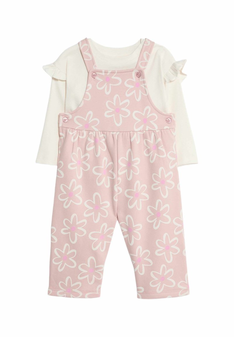 Rosa Blumendruck-Latzhose mit Trägern und Knöpfen, kombiniert mit einem weißen Langarmshirt mit Rüschensleeves.