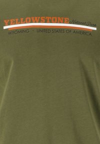 Olivenfarvet bomulds t-shirt med teksten "YELLOWSTONE National Park" i rød og sort, med "WYOMING • UNITED STATES OF AMERICA" nedenfor.