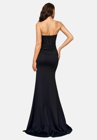 Schwarzes, figurbetontes Abendkleid mit einem trägerlosen Design, Raffung auf der Rückseite und weit schwingendem Saum. Sanfte Textur und elegante Silhouette.