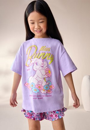 Fioletowy bawełniany t-shirt z nadrukiem kreskówkowego króliczka otoczonego kwiatami, krótki rękaw i luźny krój. W zestawie kolorowe, kwieciste spodenki.