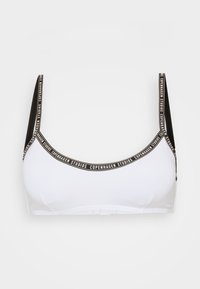 Bralette bianca con spalline nere. Presenta una fascia con il logo con il testo "Copenhagen Studios". Texture morbida e design delle coppe semplice.