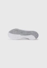 Hvit og grå Nike-sneakersåle med teksturert mønster og sentral swoosh-logo som vender oppover på en ensfarget bakgrunn.