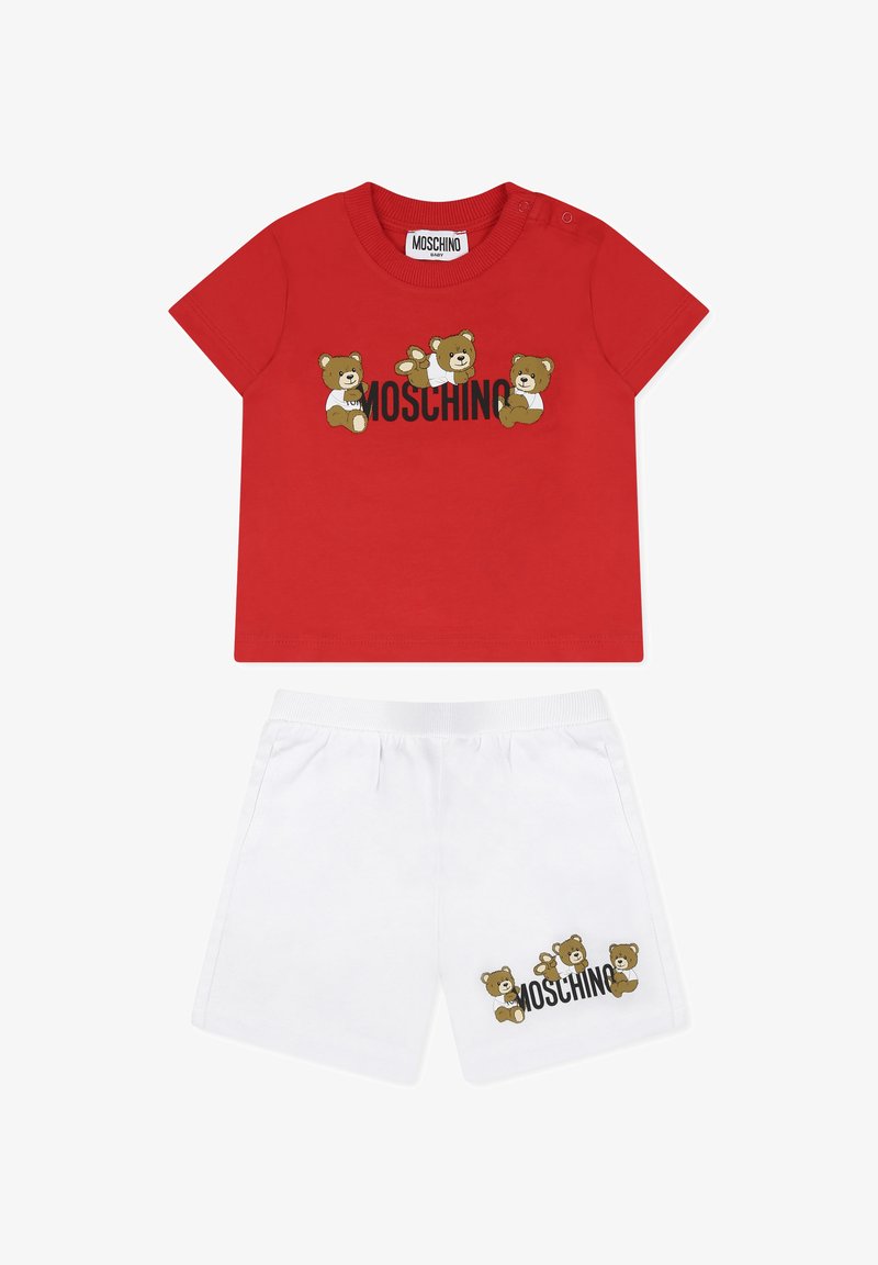 T-shirt in cotone rosso con grafiche di orsi e logo "Moschino", abbinato a pantaloni corti bianchi in cotone con motivi di orsi simili e branding.