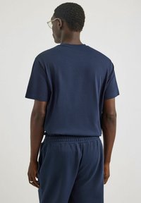 Granatowa bawełniana koszulka z klasycznym okrągłym dekoltem i krótkim rękawem, charakteryzująca się luźnym krojem i gładką teksturą.