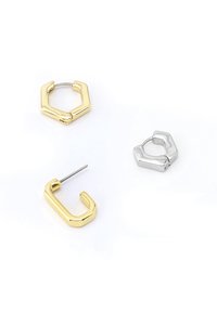 Des boucles d'oreilles en métal doré et argenté présentent des formes géométriques : un hexagone avec un anneau, une forme en U dorée et un clou d'oreille hexagonal en argent.