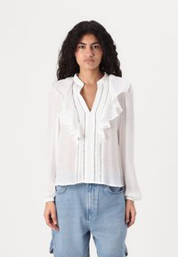 Weißes Blusenshirt mit Rüschensaum, gestreiftem Design und langen Ärmeln. Hergestellt aus leichtem Stoff, mit Knöpfen entlang der Vorderseite.