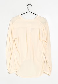 Blusa lunga beige chiaro a maniche lunghe con scollo rotondo, tessuto morbido, leggera trasparenza sulle spalle e dettaglio plissettato sul retro.