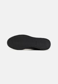 Black rubber shoe sole with a textured, patterned grip. Smooth edges with a slight curve, featuring embossed brand name "BOSS" near the heel.