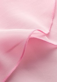 Helles Rosa, glattes Gewebe mit einer weichen Textur, das zarte Kanten und ein gefaltetes Erscheinungsbild aufweist und subtile Nähte betont.