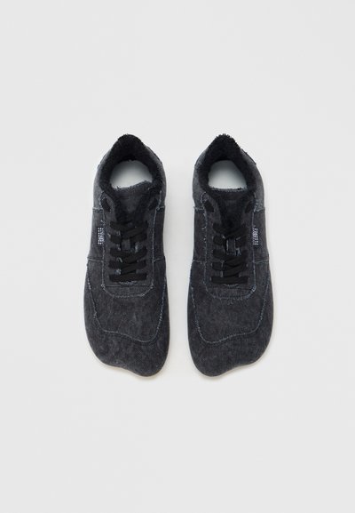 Μαύρα υφασμάτινα αθλητικά παπούτσια με υφή στην επιφάνεια, σχέδιο με κορδόνια, επενδεδυμένος γιακάς και αντίθετη ραφή. Στρογγυλεμένο σχήμα μύτης.