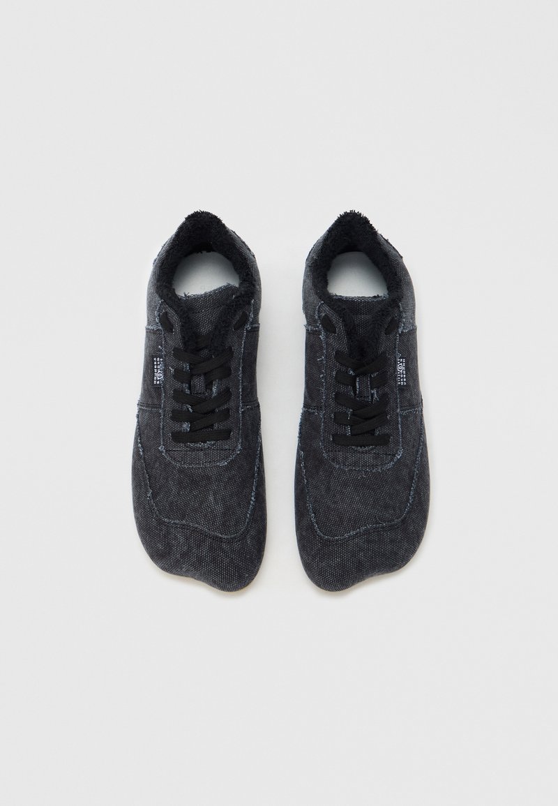 Sorte stofsneakers med en struktureret overflade, snørelukning, polstret krave og kontrastfarvet syning. Rundet tåsform.