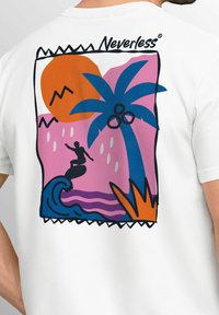White t-shirt featuring a colorful graphic design with a surf scene, palm tree, sun, waves, and bold outlines in pink, orange, and blue.