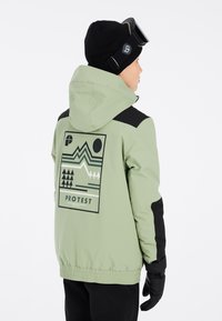 Grüne Skijacke mit schwarzen Akzenten, die ein geometrisches Grafikdesign auf dem Rücken zeigt. Die Jacke hat eine Kapuze und einen elastischen Bund.