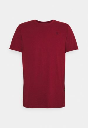 Gładka ciemnoczerwona koszulka z krótkim rękawem i okrągłym dekoltem, z małym logo na lewej piersi oraz metką przy dolnym brzegu po prawej stronie.