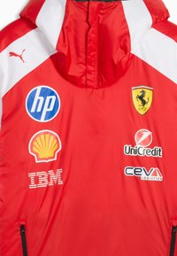 Red racing jacket with white accents featuring Puma, Ferrari, HP, Shell, IBM, UniCredit, and CEVA Logistics logos on the front.