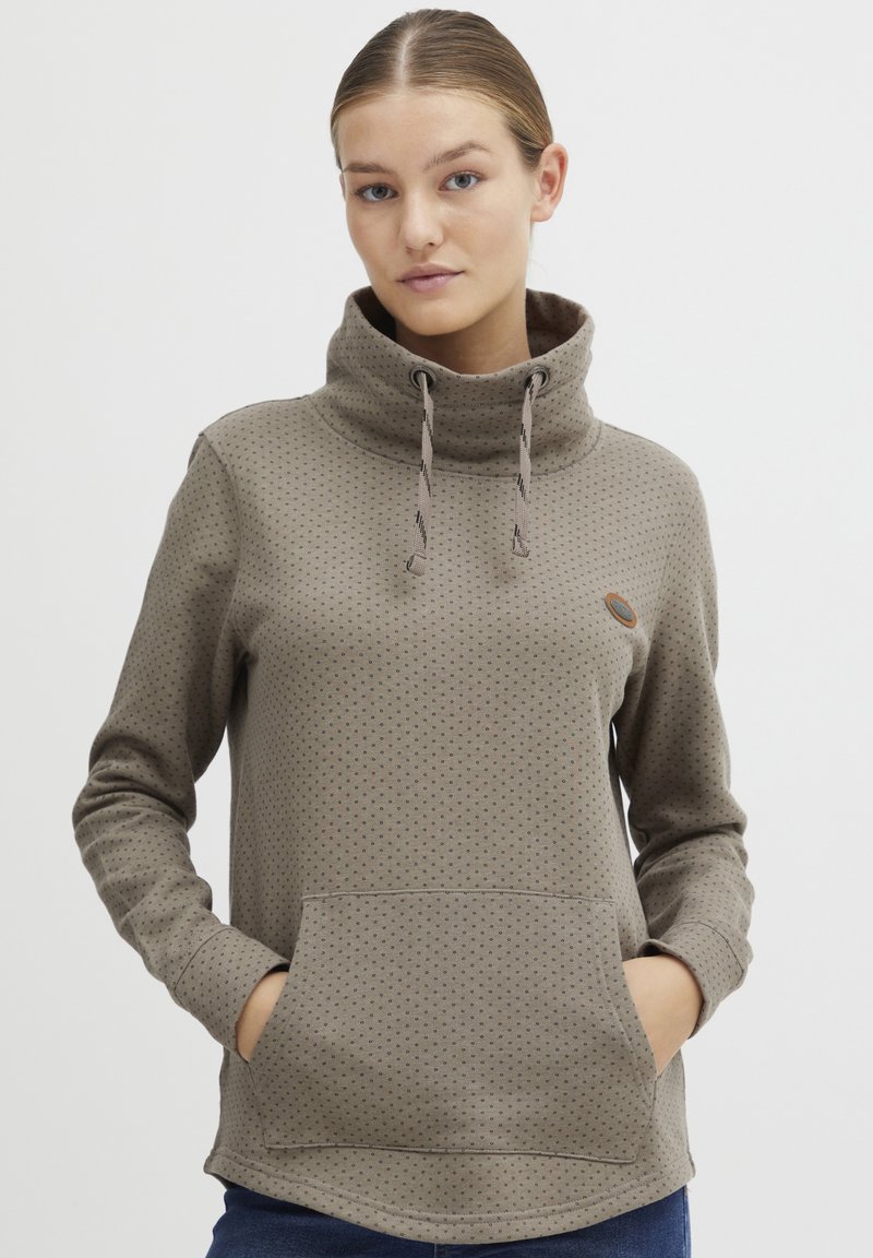 Pullover marrone chiaro con collo alto, lacci, motivo a pois e tasca a marsupio frontale. Materiale morbido con vestibilità rilassata.