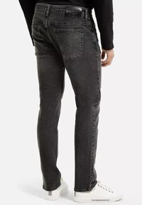 Ciemnoszare dżinsy z wąskim krojem, z tylnymi kieszeniami i metką na pasie, w połączeniu z białymi trampkami.