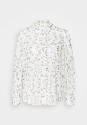 Blouse blanche à manches longues avec imprimé floral gris, col montant à volants et bordure à volants le long de la patte de boutonnage.