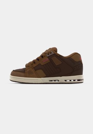 Brun sneaker med en blanding af glatte og perforerede teksturer. Har et buet design, polstret krave og en hvid mellemsål med luftlommer.