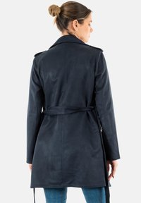 Trench coat in ecopelle blu navy con maniche lunghe, vita con cintura e distintive spalline. Texture liscia con una finitura elegante.