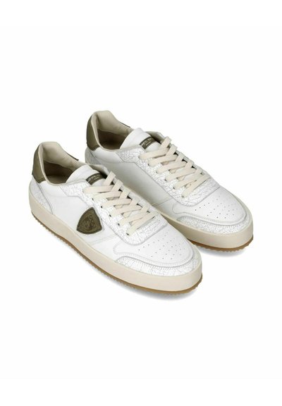 Hvide lædersneakers med lysegrønne accenter, teksturerede sidepaneler, perforeret tåboks og flade beige snørebånd. Blød indvendig polstring.