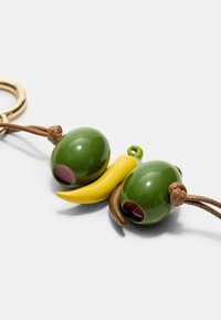 Vihreä kiiltävä avaimenperä, jossa on kaksi pyöreää oliivimuotoa, joista toisessa on syvän burgundin värinen keskus, sekä kaareva keltainen chili-paprika ja ruskeat yksityiskohdat.