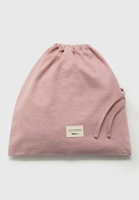 Mjuk rosa dragsnöre väska gjord av slät tyg, med en rektangulär etikett som har texten "SLEEPWEAR COLLECTION" och varumärkesnamnet.