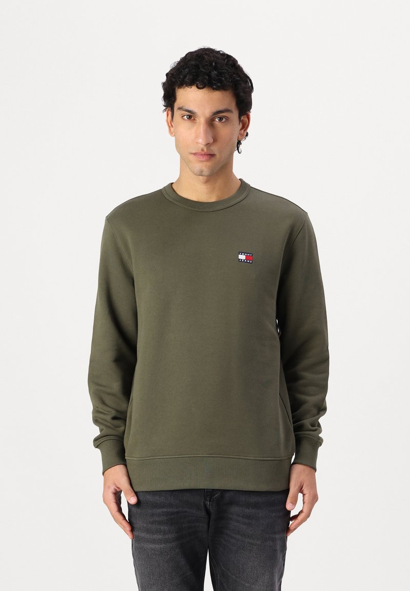 Sweatshirt verde-oliva em material suave, apresentando um decote redondo e punhos canelados. Pequeno logotipo no lado esquerdo do peito.
