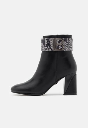 Bottine en cuir noir avec un talon rehaussé, dotée d'une bande en imprimé serpent distinctif et d'un accent métallique "B" sur la sangle.