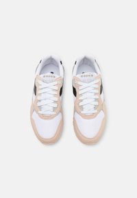 Tenisky s bílým síťovaným svrškem, béžovými semišovými doplňky a černými bočními detaily. Mají ploché bílé tkaničky a polstrovaný jazyk pro pohodlí.