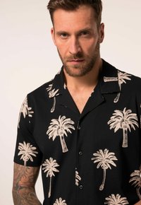 Camisa negra de manga corta con patrones de palmeras blancas, diseño de cuello y botones en frente. Confeccionada en tela ligera.
