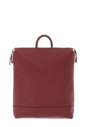Sac à dos en cuir rouge avec un design structuré, une poignée supérieure et une fermeture à glissière. Il possède une texture lisse et une marque minimaliste en bas.