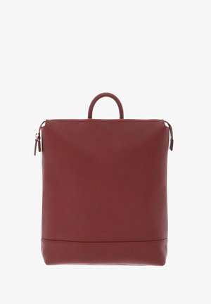 Sac à dos en cuir rouge avec un design structuré, une poignée supérieure et une fermeture à glissière. Il possède une texture lisse et une marque minimaliste en bas.