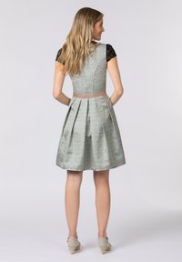 A light green dress with a floral pattern, pleated skirt, and a textured black lace cap sleeve. It has a contrasting pink waistband.