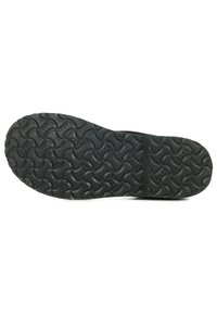 Suela de zapato de goma negra con un patrón de banda de rodadura ondulado y acentos elevados, que proporciona mayor tracción y durabilidad.